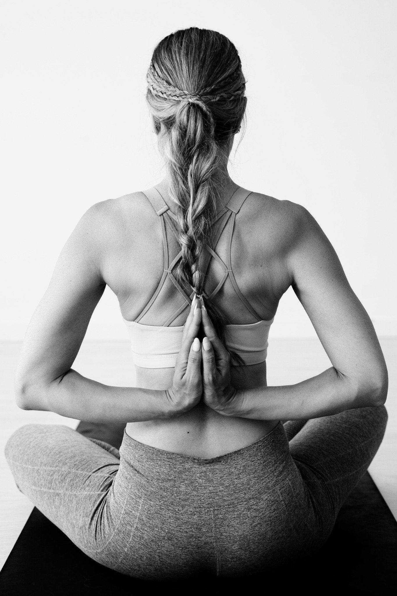 una-mujer-sentada-en-la-posicion-del-loto-con-las-manos-en-anjali-mudra-en-la-espalda_compressed